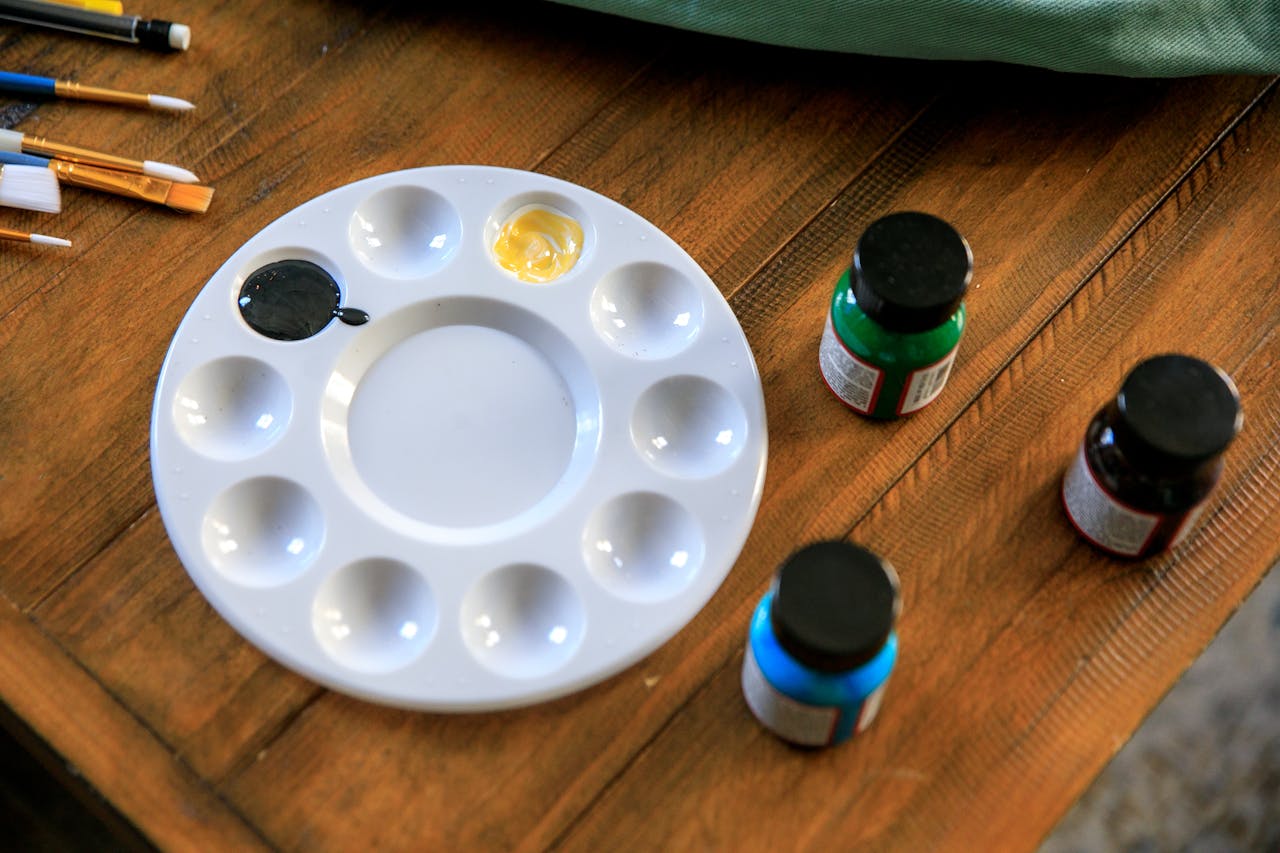 heros-img Art supplies arranged on a wooden table with a palette and various paints. Ideal for art-themed projects.